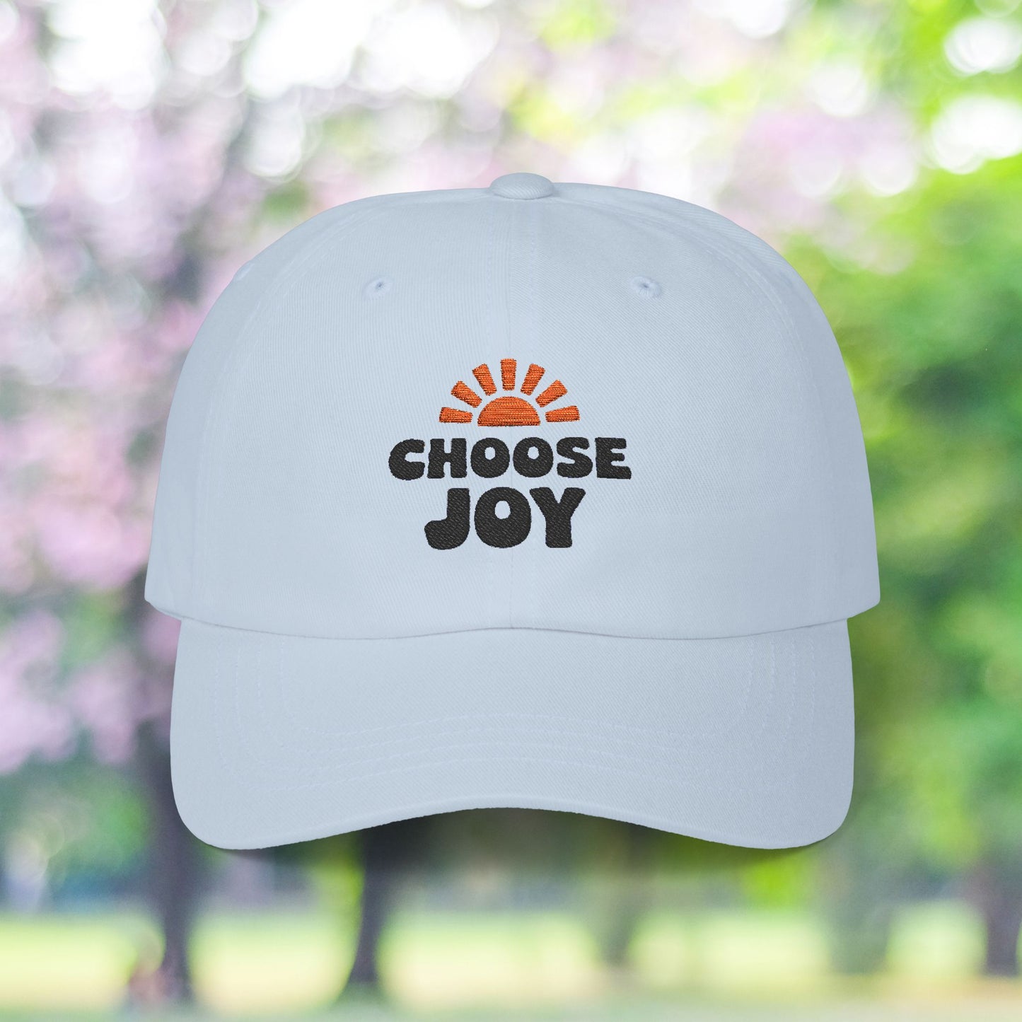 White baseball cap with 'Choose Joy' sun graphic.