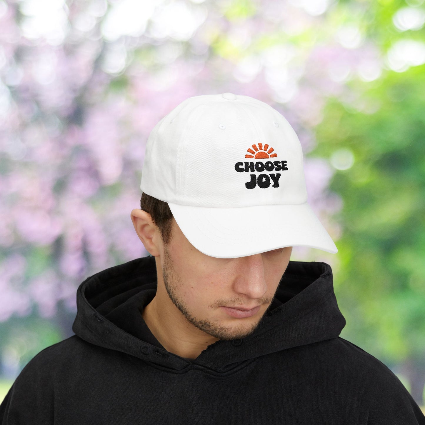 White baseball cap with 'Choose Joy' sun burst graphic.