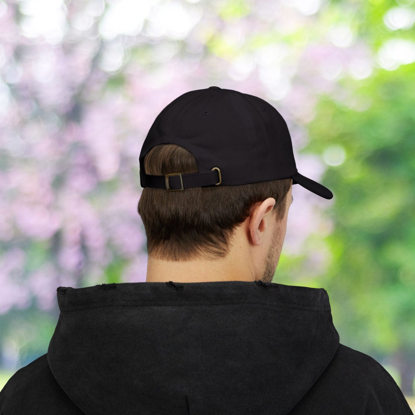 Black classic baseball hat with adjustable strap on a person.