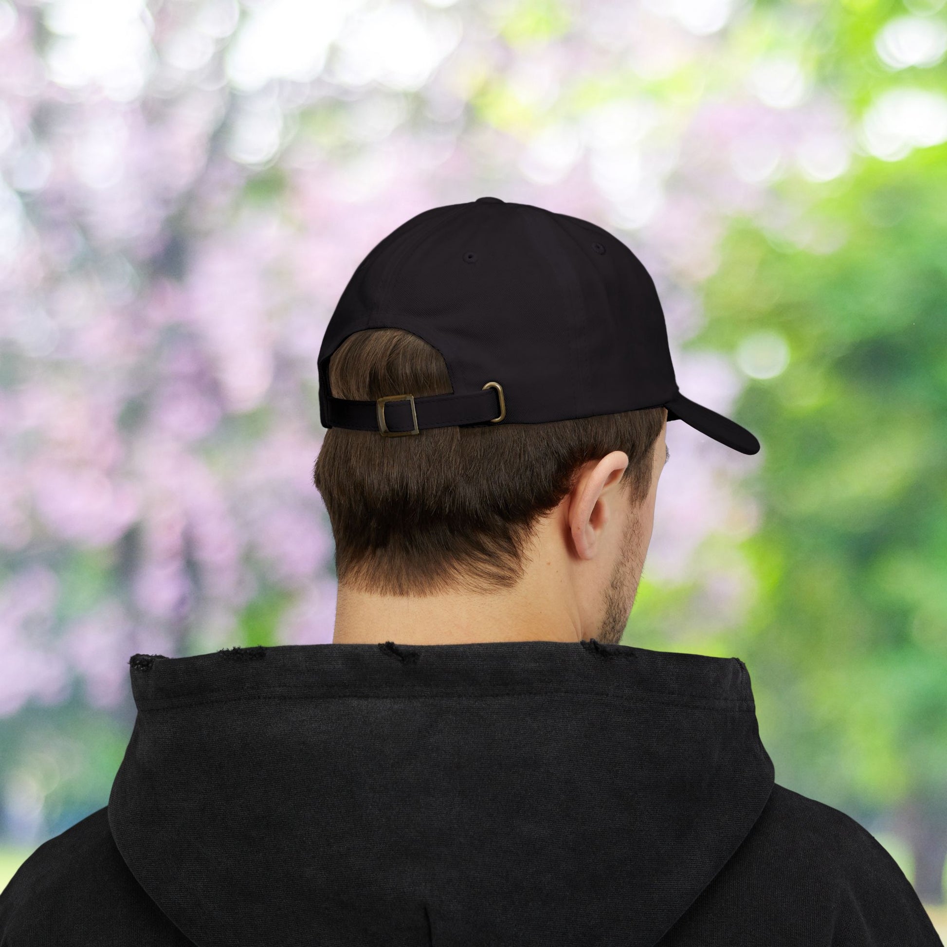 Black classic baseball hat with adjustable strap on a person.