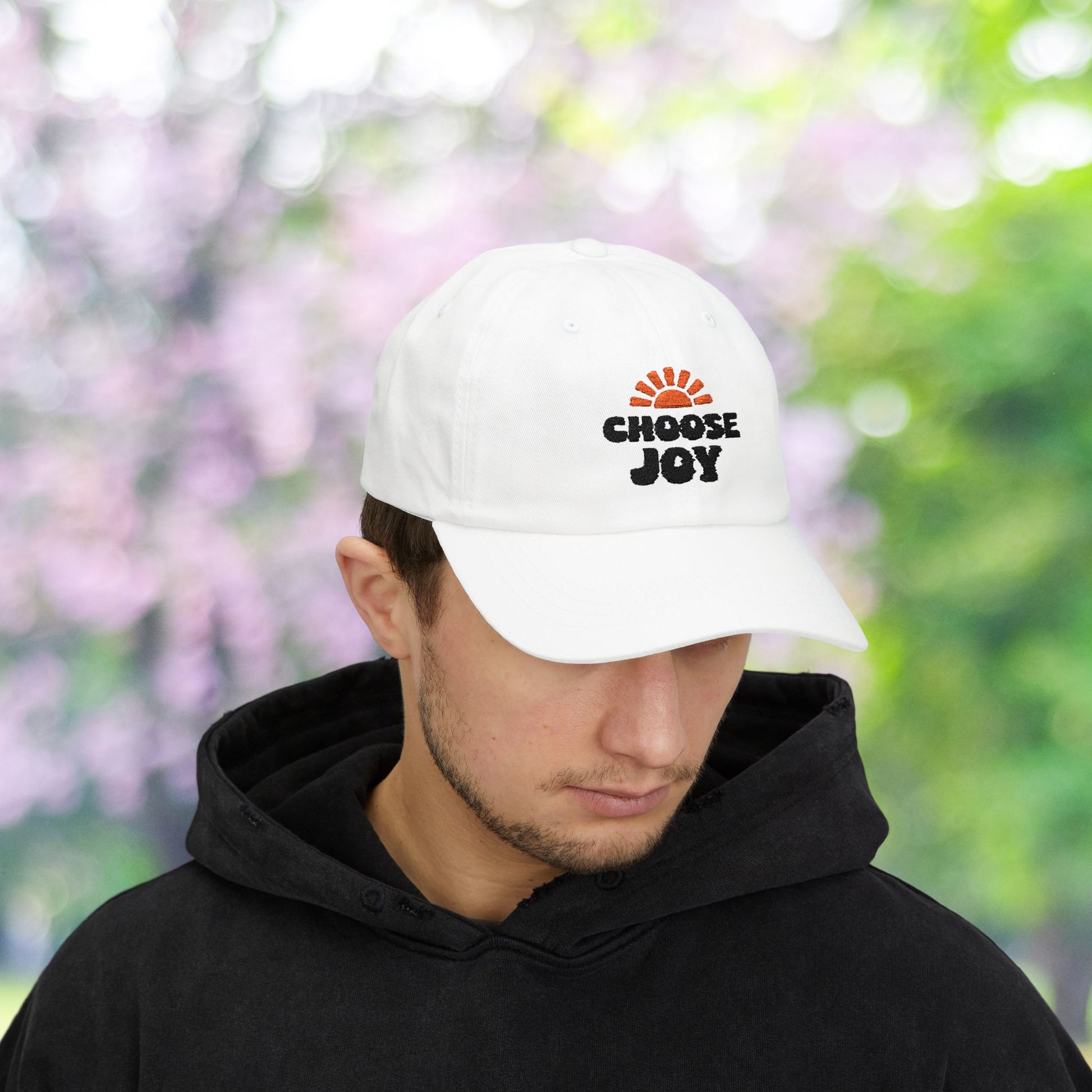 White baseball cap with 'Choose Joy' sun burst graphic.
